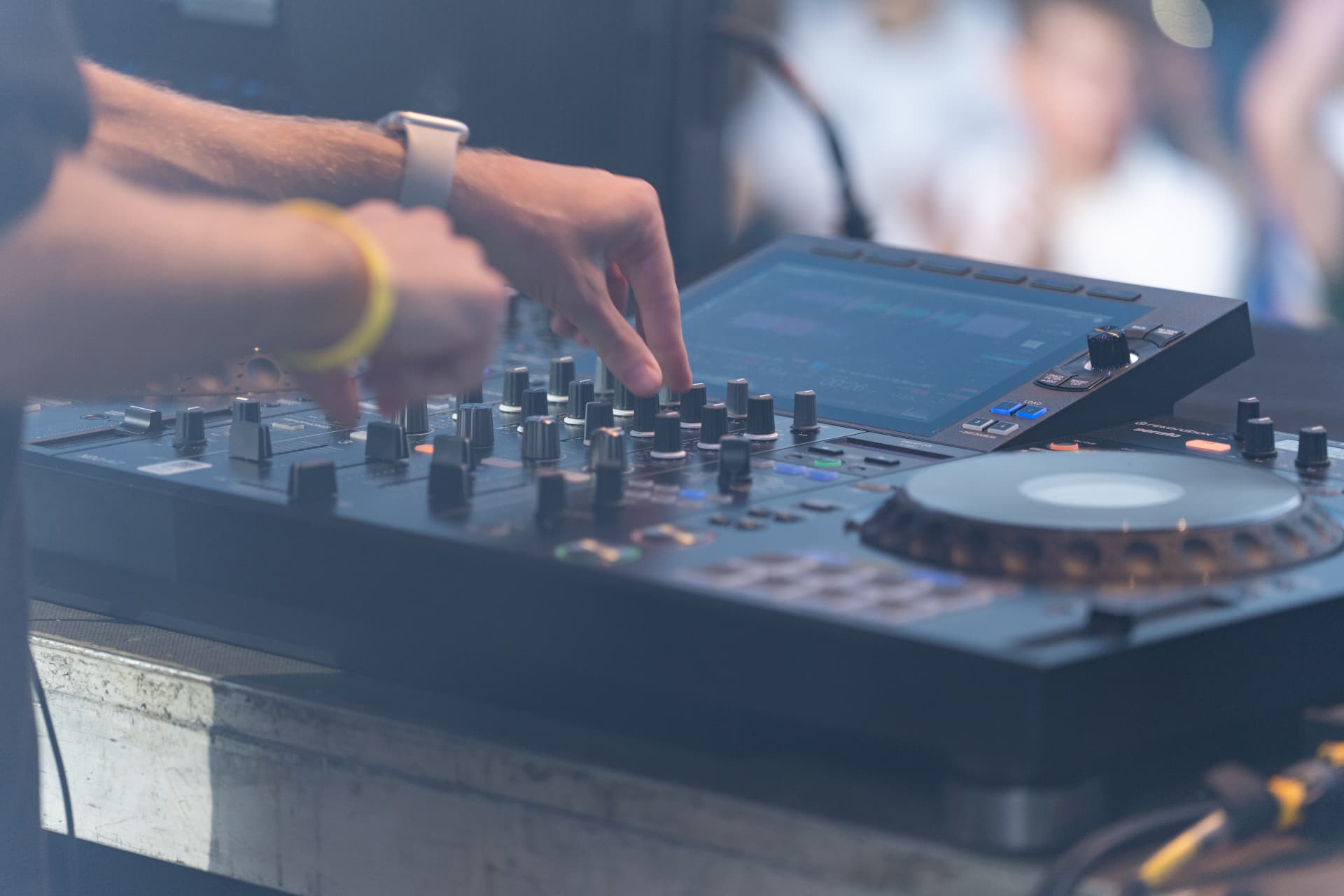 Detailaufnahme der Hände am DJ-Mixer während des Sets